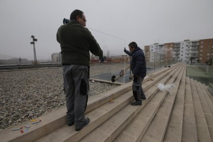 Dos operarios, instalando ayer las nuevas mamparas en las escaleras frente a la Llotja.