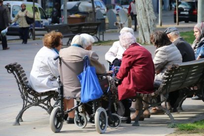 Un grupo de jubilados sentados en un banco de la ciudad de Lleida. 