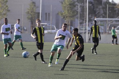 Jugadors de l’equip local i del visitant es disputen la pilota.