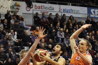 Gerard Sevillano entra a cistella defensat per Tautvydas Sabonis i Gediminas Zyle, jugadors del Corunya.