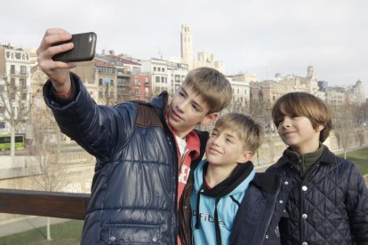 Jóvenes se hacen un 'selfie' este jueves con la Seu Vella y la canalización de fondo iluminadas por el sol.