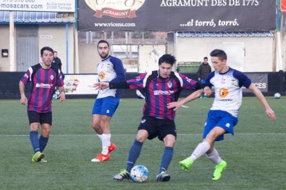 Un jugador del EF Tàrrega y otro del Guissona B luchan por un balón ante la mirada de sus compañeros.