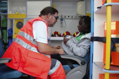 Un membre dels serveis de salvament atén una dona embarassada arribada en una pastera.