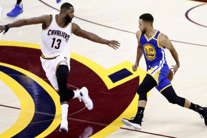 Stephen Curry passa la pilota per l’esquena per driblar la defensa de Tristan Thompson.