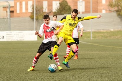 El jugador del Balaguer Sergi pugna amb un del Rubí pel control de l’esfèrica al centre del camp.