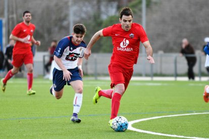 Un jugador del Alpicat se escapa con el balón en los pies ante la persecución de un jugador local.