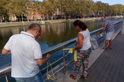 Varias personas colocan lazos amarillos en las cercanías del museo Guggenheim de Bilbao.