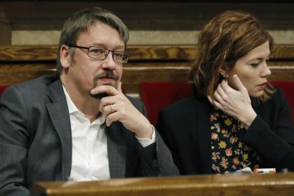 Los diputados de En Comú Podem, Elisenda Alemany (d) y Xavier Domenéch (i), durante el pleno del Parlament celebrado hoy para votar una propuesta de JxCat para legitimar a Carles Puigdemont que, aunque finalmente no incluirá la propuesta de la CUP de reafirmar la declaración unilateral de independencia, contará con el apoyo de los anticapitalistas y de ERC