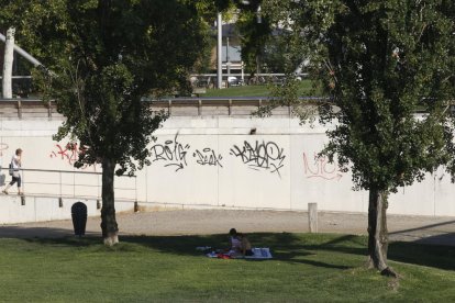 Dos joves es protegien ahir de la calor a l’ombra dels arbres a prop del riu Segre.