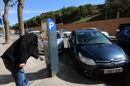 Un usuario de la zona azul, recogiendo el tiquet del parquímetro.