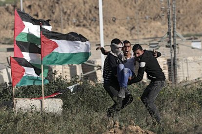 Varios manifestantes palestinos retiran a un joven que resultó herido en la frontera entre Israel y Gaza.