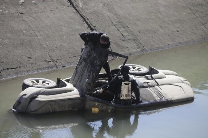 Imagen de los dos vehículos en el interior del canal. En la foto de la derecha, los buzos de los Mossos inspeccionando uno todoterreno. 