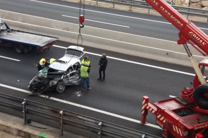 El cotxe, que es va precipitar al buit sobre l'autovia A-7, abans de ser carregat sobre la grua.