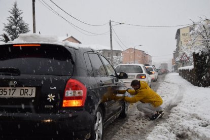 Un conductor instalando por la mañana cadenas en las ruedas de su coche en el pueblo de Adrall. 