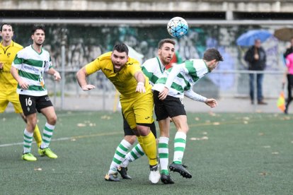 Un jugador del EFAC cae durante la disputa de un balón ante dos jugadores del Sants.