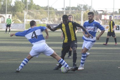 Un jugador de l’equip visitant intenta prendre la pilota a un del local. 