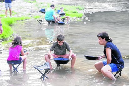 Pequeños y mayores buscan particulas de oro en el río mediante el antiguo proceso de tamizado. 