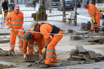 Operaris treballant en unes obres a la via pública.