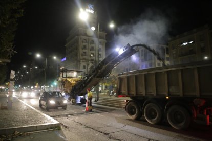 Una máquina retira el asfalto de avenida de Madrid mientras pasan dos vehículos por el carril abierto aún al tráfico, ayer por la noche. 