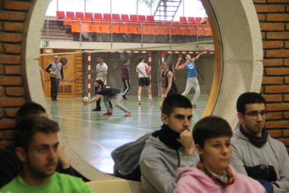 Alumnos de Inefc durante una clase teórica y tras ellos otros practicando voleibol en el pabellón.