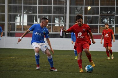 Un jugador de l’Alpicat intenta controlar una pilota davant de l’oposició d’un rival del Lleida B.