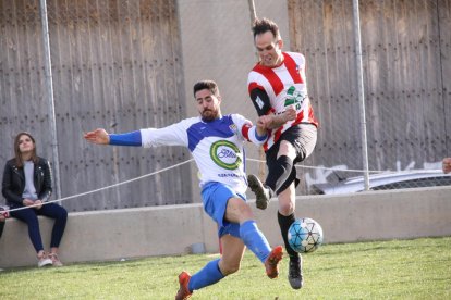 Un jugador del Bellcairenc golpea el balón pese a la presión rival.