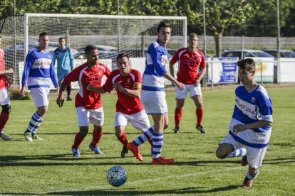 Un jugador local intenta controlar la pilota davant la pressió dels visitants. 