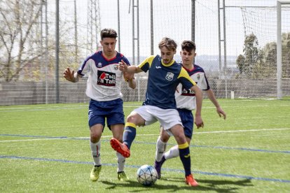 Dos jugadores del Sant Ildefons presionan a un jugador del Borges, que intenta proteger el balón.