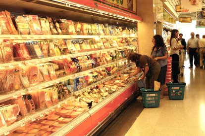 Diverses persones fent la compra en un supermercat.