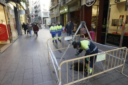 Un operari treballant al clavegueram al carrer Major.