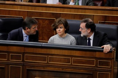 La vicepresidenta Soraya Sáenz de Santamaría, flanqueada por Rafael Catalá y Mariano Rajoy, ayer.