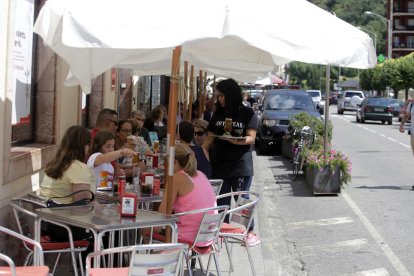 Una cambrera serveix les taules d’una terrassa plena de clients a Sort.