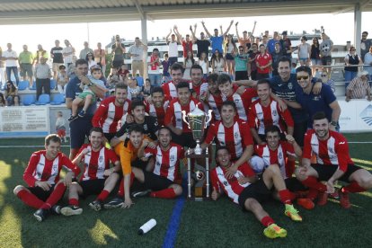 Els jugadors i el cos tècnic del Puigvertenc celebren el títol amb part de l’afició al fons.