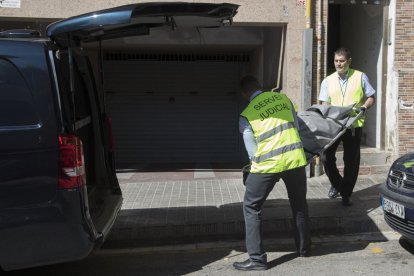 Membres del servei judicial retiren el cadàver de la dona que ha estat assassinada presumptament per la seva parella al seu domicili de Badalona