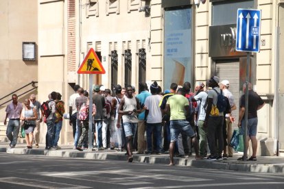 Usuaris de la Fundació Jericó feien cua ahir a la parròquia del Carme per recollir un tiquet per al dinar que serveixen després al carrer Tallada.