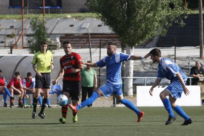 Un jugador de l’EFAC lluita una pilota amb un jugador del Sants amb el col·legiat al fons.