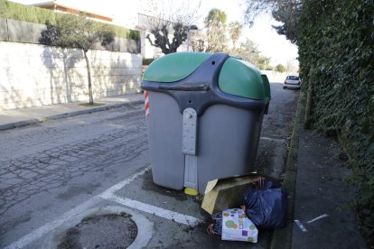 Basura en el suelo junto a un contenedor de vidrio.