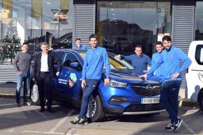 Algunos jugadores y técnicos posan ayer con los vehiculos que Opel Lleidamobil cede al club.