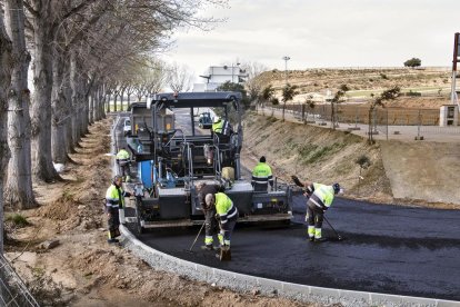 Operaris asfaltant ahir uns dels accessos situats darrere de la graella de sortida.