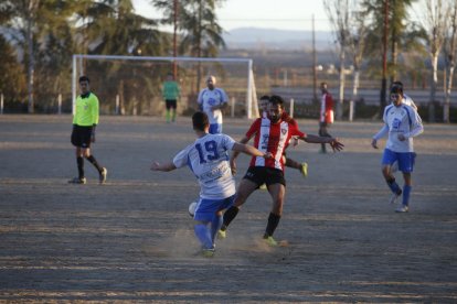 Un jugador del equipo local y uno del visitante compiten por el balón.