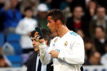 Cristiano se mira en un móvil el corte que se hizo durante el partido y que precisó de un par de puntos.