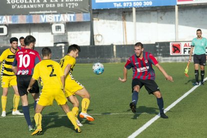 Un jugador de la UE Tàrrega intenta passar una pilota entre dos defensors rivals durant el partit.