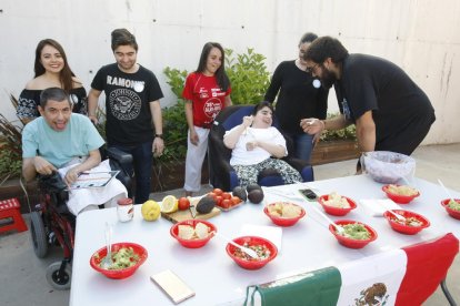 Un estudiant d’Educació Social dona a provar guacamole mexicà a una resident d’Aremi.