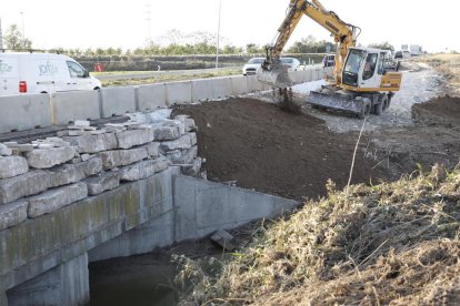 Una excavadora reponiendo el material arrastrado en la N-240.