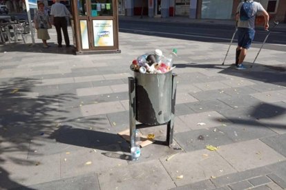 Una de las papeleras llenas, en la plaza del Treball