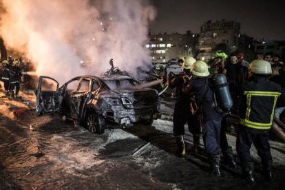 Els bombers sufoquen les flames en un dels vehicles incendiats.