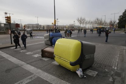 Contenidors bolcats i, al fons, autobusos aturats.