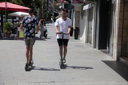 Dos usuarios  de patinetes eléctricos circulando por Lleida.