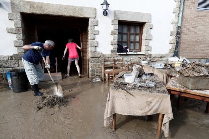 Veïns miren de netejar la casa després de les riuades.