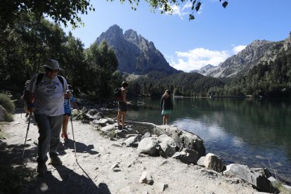 Senderistes a l’Estany de Sant Maurici, amb els Encantats al fons.